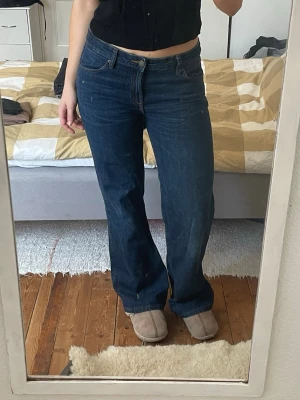 Mörkblå bootcut jeans - Säljer ett par mörkblå bootcut Zara jeans med klassisk femficksdesign och låg midja. Jeansen har en lätt utsvängd passform nertill och stängs med dragkedja och knapp. Perfekta för en avslappnad och trendig look.