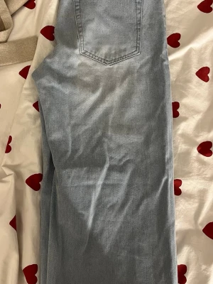 Ljusblå raka jeans från Weekday - Säljer ett par ljusblå jeans från Weekday med klassisk femficksdesign och raka ben. Jeansen har bälteshällor och knappgylf. Perfekta för en avslappnad och trendig stil. Materialet är denim i bomull.