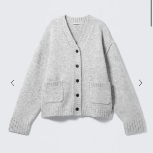 Ljusgrå kofta med knappar Weekday - Mysig ljusgrå kofta från Weekday med v-ringning och stora svarta knappar framtill. Två rejäla fickor fram och ribbade muddar vid ärmslut och nederkant. Perfekt för lager på lager och chill stil.