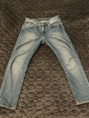 Levi's 502 blå jeans W30 L30 - Klassiska blå jeans från Levi's modell 502 med raka ben och normal midja. Jeansen har fem fickor, dragkedjegylf och snyggt slitna detaljer för en avslappnad look. Perfekta till vardagsstilen och funkar året runt. (Pris går att diskutera)