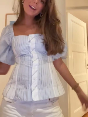 Ganni blus  - Super snygg Ganni blus,  blus med ljusblå och vita ränder, puffiga korta ärmar och knappar framtill. Fyrkantig urringning 😝