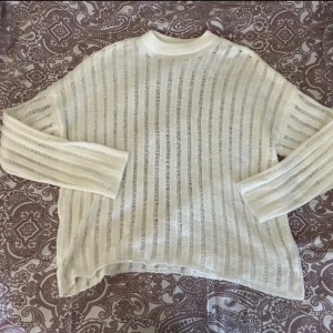 Vit randig stickad tröja från NA-KD - Säljer en vit stickad tröja från NA-KD i storlek S. Tröjan har ett transparent, randigt mönster och är långärmad med en loose passform. Perfekt för lager-på-lager och ger en chill vibe till din outfit. Stor i storleken 