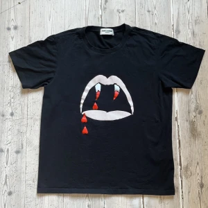 Saint Laurent - Blood Luster T-shirt - Saint Laurent Paris T-shirt designad av Hedi Slimane för Saint Laurent. Svart, storlek M, passar S eller Slim M. Mått: Längd: 56 cm Bredd: 41 cm