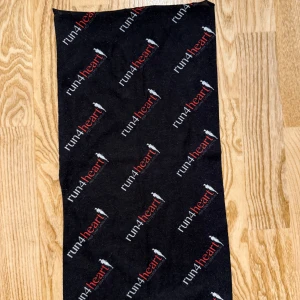 Svart halsduk Run4Heart - Svart tubhalsduk med tryckt Run4Heart-logga i vitt och rött över hela tyget. Perfekt accessoar för löpning eller utomhusaktiviteter. Mjuk och smidig att bära runt halsen.