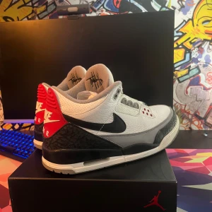 Air Jordan 3 Retro Tinker Hatfield storlek  - Säljer ett par Air Jordan 3 Retro 'Tinker Hatfield' sneakers i vitt, svart och grått med röda detaljer. Skorna har klassisk elefantmönstrad panel, svart swoosh och röd hälkappa med Nike Air-logga. Ovandel i skinn och robust sula med synlig Air-enhet. Box medföljer.