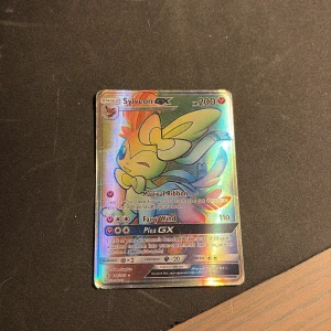 Sylveon GX - Sylveon GX är ett glittrande och färgstarkt samlarkort från Pokémon-serien. Perfekt för dig som älskar att samla, spela eller bara vill ha en snygg och unik Pokémon till din samling. Kortet har coola attacker och passar både nya och erfarna samlare.