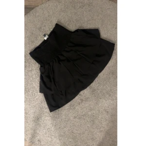 Svart volangkjol ifrån seaside - Supersöt svart kortkjol med volangig nederdel. Kjolen har en luftig känsla och passar perfekt till sneakers eller boots. Enkel att matcha och ger en cool vibe till din outfit.