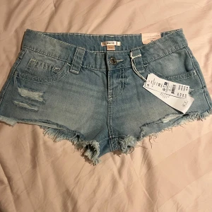 Ljusblå denimshorts från Gina Tricot - Säljer ett par ljusblå denimshorts från Gina Tricot i modell xtra low. Shortsen har fransig kant, slitningar framtill och snygga silverfärgade nitar på bakfickorna. Aldrig använda och har lappen kvar. nypris 300!💕