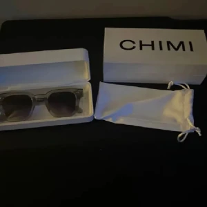 Grå CHIMI solglasögon. - Snygga solglasögon från CHIMI med transparent grå båge och fyrkantig form. Kommer med original box och vit tygpåse. Perfekt accessoar för att lyfta din stil under soliga dagar. Pris kan diskuteras.