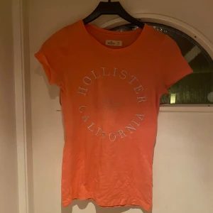 Orange/aprikos t-shirt från Hollister XS - Snygg t-shirt från Hollister i storlek XS. T-shirten har rund halsringning, korta ärmar och tryckt text 'Hollister California' framtill. 