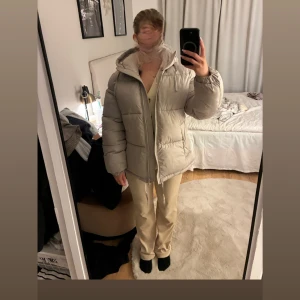 Beige pufferjacka från H&M XS - Säljer en beige pufferjacka från H&M i storlek XS. Jackan har huva, dragkedja framtill och är quiltad med en oversized look. Perfekt för kalla dagar och riktigt skön att bära. Färgen är ljusbeige och materialet är syntet.