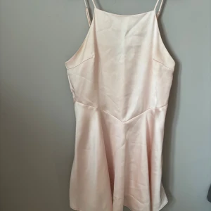 Champagnefärgad satin klänning Zara - Säljer en elegant kortklänning från Zara i ljusrosa satin. Klänningen har smala axelband och en mjukt utsvängd nederdel som ger en snygg siluett. Perfekt för dig som gillar minimalistisk stil med lyxig känsla.