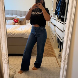 Blå raka jeans med en hög midja - Säljer ett par klassiska blå jeans med hög midja och raka ben. Jeansen har en enkel design utan slitningar och är tillverkade i ett stadigt denimtyg. Perfekta för dig som gillar en clean och tidlös look.