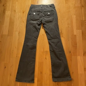 Grå bootcut jeans från True Religion - Grå jeans från True Religion i modellen Becca med bootcut. Midjemåttet rakt över är 32cm och innerbenslängden är 78cm. Skriv gärna för mer info eller bilder på jeansen 💕