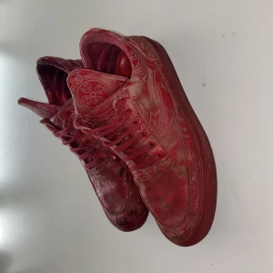 Röda fealing pieces sneakers med olika mönster - Unika röda fealing pieces sneakers med detaljerat mönster över hela skon. Skorna har snörning, platt sula och rund tå. Materialet är skinn och de har en cool, konstnärlig vibe med sina grafiska mönster. Perfekt för dig som vill sticka ut med dina sneakers.