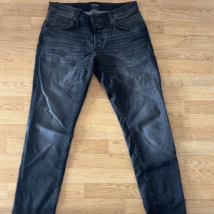 Slim Glenn svarta jeansbyxor 34/34 - Svarta jeansbyxor från Jack & Jones i model Slim Glenn i storlek 34/34. Modellen har en slim passform med klassisk femficksdesign och subtila slitningar för en cool look. Jeansen är tillverkade i stretchigt denim för extra komfort och sitter snyggt längs benen. Nypris 899kr och säljes för ett bra pris!!