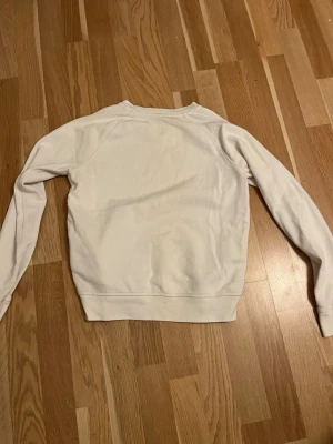 Vit sweatshirt från Levi's XS - Säljer en vit sweatshirt från Levi's i storlek XS. Tröjan har klassisk rund hals och långa ärmar, med det ikoniska Levi's-logotypen tryckt i rött framtill. Mjuk och skön bomullskvalitet, perfekt för chill dagar. Enkel och stilren design som funkar till jeans eller leggings.