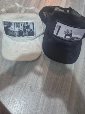 Fina velvet kepsar i bra skick - Bilderna visar två kepsar, en svart från OneCap och en vit från Emilio Pendienza, båda med mesh och tryck framtill. 