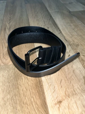 Svart bälte i fejk läder - Ett bälte som jag aldrig fått användning av. Svart i fejk läder med flertal hål, köpt i storlek S från SHEIN