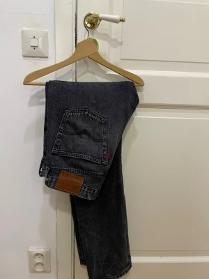 Levi's 501 svarta jeans - Säljer ett par klassiska Levi's 501 jeans i mörkblå-svart tvätt. Jeansen har raka ben, fem fickor och den ikoniska läderlappen bak. Materialet är robust denim i bomull och passformen är straight. Jeansen sitter som 30/32