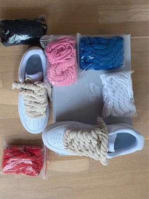 Nike Air Force 1 med tjocka snören - Beskrivning  Unika vita Air Force 1 med exklusiva rope-snören  Ge din stil en helt ny edge! Dessa vita Air Force 1 för män kommer med 6 olika färger på snören så du kan variera looken efter humör och outfit. Ord. pris 2000 kr nu endast 1000 kr. först till kvarn!