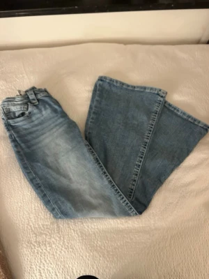 Blå bootcut jeans med detaljer - Snygga ljusblå jeans från Gina Tricot med bootcut passform. Jeansen har dekorativa sömmar och små nitar på bakfickorna som ger extra stil. 