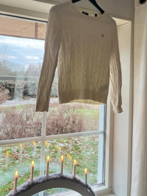 Vit kabelstickad tröja från GANT - Säljer en klassisk vit kabelstickad tröja från GANT med rund hals. Jättefin och i bra skick!!😍passar S och XS storleksmässigt 