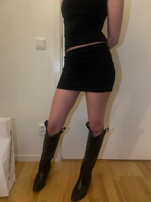 Svart tight minikjol - Säljer en svart, tight minikjol med enkel design och stretchigt material. , perfekt för dig som gillar en clean och stilren look. Passar dig som vill ha en klassisk svart kjol som är lätt att matcha med olika toppar.