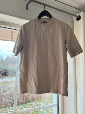 Beige t-shirt från ZARA  - Säljer en stilren beige t-shirt från ZARA med högre krage och trekvartsärm. Jättesnygg tröja 