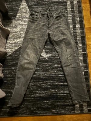 Jeans jack&jones - Säljer ett par gråa skinny jeans från jack &jonesmed klassisk femficksmodell och svarta detaljer på bakfickorna. Jeansen har en smal passform och är tillverkade i mjukt denimtyg. Perfekta för dig som gillar en stilren och enkel look. Aldrig använt typ💯29/32