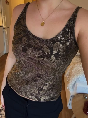 Glittrig mönstrat  linne / topp från Benetton - En glittrig linnetopp från Benetton i svart och guld med mönster.