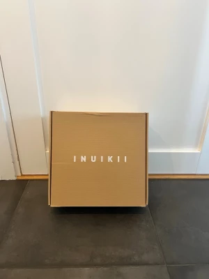 Svarta Inuikii boots med snörning - Säljer ett par svarta Inuikii boots med grov snörning och platt sula. Skorna har en rund tå och är fodrade för extra värme. Utsidan är i mocka och skinn, vilket ger en snygg och robust look. Perfekta för kalla dagar och vinterväder.Använda 1 gång inhomhus 