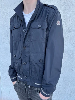 Moncler jacka - Säljer denna ruskigt snygga jacka från Moncler! Skick 9/10 - inga defekter. Nypris 7999kr, mitt pris endast 2199kr. Storlek 4, passar M/L (modellen är 186 cm). Hör av er vid funderingar!
