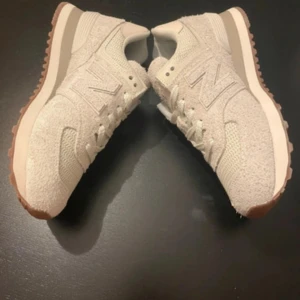 Beige & ljusgrön New Balance 574 sneakers - Snygga New Balance 574 sneakers i beige & ljusgrön med grov mocka och meshdetaljer. Klassisk siluett med rund tå, snörning och vit mellansula. Yttersulan är i gummi med bruna detaljer. Perfekta för dig som gillar stilrena och bekväma sneakers. Butikspris 1400 kr. Storlek 39 & 25 cm 