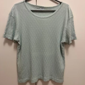 Ljusgrön ribbad topp i 100% bomull strl 50/52 - Ljusgrön ribbad topp i 100% bomull med korta ärmar och rund hals. Toppen har fläckar (se bild). Storlek 50/52.