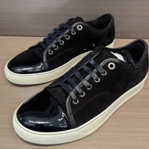 Svarta sneakers från Lanvin med lackad tå - Snygga svarta sneakers från Lanvin med vit platt sula och snörning. Ovandelen är i mocka och tån är i blankt lackskinn som ger en cool kontrast. Metallfärgade öljetter och klassisk rund form. Perfekta för dig som gillar stilrena och exklusiva sneakers.