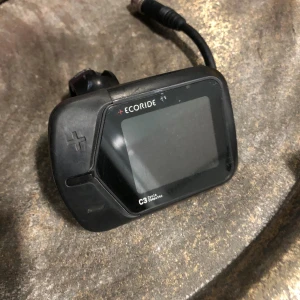 Ecoride C3 Cycle Computer - Ecoride C3 Cycle Computer till elcykel. Displayen har tydliga knappar och anslutningskabel. Monteringsfäste ingår. Skärmen är repfri, men viss yttre slitage syns på plasten. Perfekt för dig som behöver ersätta eller uppgradera din elcykeldisplay.