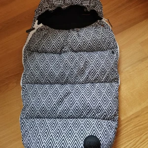 Mönstrad åkpåse Petite Chérie Design/Vognpose - Snygg åkpåse från Petite Chérie Design med svartvitt grafiskt mönster. Yttermaterialet är i polyester och har dragkedja på sidorna. Perfekt för att hålla värmen under kalla dagar och passar de flesta barnvagnar.