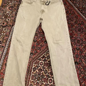 Beige jeansbyxor från Gizmo, storlek L - Snygga beige jeansbyxor från Gizmo i storlek L. Klassisk femficksmodell med raka ben och normal passform. Byxorna har bälteshällor och dragkedja fram. Materialet är slitstarkt och mjukt bomullstyg som ger en skön känsla hela dagen.