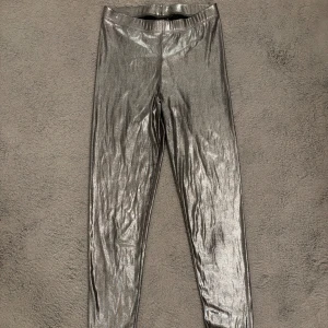 Skimriga silverleggings från Lindex - Snygga och skimriga silverleggings från Lindex i storlek M. De har en tight passform och är tillverkade i ett stretchigt material. Skulle säga att de passar som S också. Använda endast en gång😊