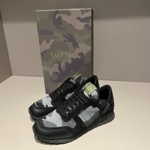 Valentino Rockrunner sneakers svart/grå - Säljer ett par Valentino Rockrunner sneakers i svart och grått med camouflage-mönster. Storlek 41,5 men är större i storlekarna. Bara använda ett få par gånger alltså ett riktigt bra skick för riktigt bra pris. Skorna är köpta på merchsweden.se för 5000kr nya. 