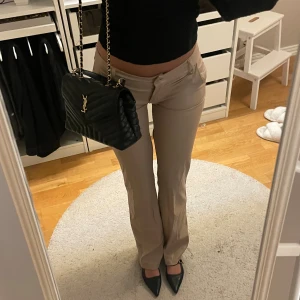 Beiga bootcut byxor med låg midja - Snygga lågmidjade beiga byxor med bootcut-snitt och låg midja. Festbyxa 