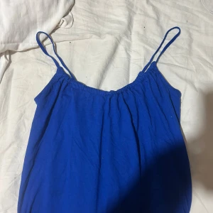 Kornblå linne från Bik Bok - Supersöt kornblå linne från Bik Bok i storlek XS. Linnet har tunna axelband och en luftig, avslappnad passform. Perfekt för varma dagar med sitt mjuka bomullsmaterial och enkla design. Den har även en öppen rygg. Säljer då den inte längre kommer till användning.