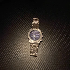 Silverfärgad Regal klocka med blå urtavla - Säljer en stilren klocka från Regal med silverfärgat metallarmband och blå urtavla med kronograf-detaljer. Urtavlan har ett rutigt mönster och boetten är åttakantig med synliga skruvar. Perfekt för dig som gillar en modern och edgy look.