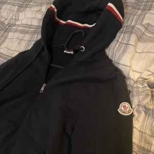 Mörkblå hoodiejacka från Moncler - Snygg mörkblå hoodiejacka från Moncler typ aldrig använd . Äkta och kvitto finns. Kan lösa mer bilder om de är så. Storlek M men passar också S .