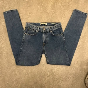 Blå smala jeans från Mango Man - Snygga blå jeans från Mango Man med klassisk femficksdesign och smal passform. Jeansen har normal midja, raka ben och är tillverkade i mjukt bomullsmaterial med lite stretch för extra komfort. Perfekta för dig som gillar en stilren och enkel look.