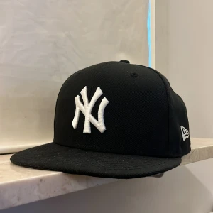 Svart new era keps - Säljer nu min svarta new era keps som knappt är använd, den passar väldigt fint och bra och är skön att ha på sig, använd kanske 4 gånger men ser ut som helt ny, kepsen är från jd sports och kostade typ 550kr tror jag så de är ett väldigt bra pris! 