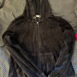 Svart velour hoodie med dragkedja - Mjuk och skön svart hoodie i velour från C. Tröjan har huva med snörning, hel dragkedja framtill och praktisk känguruficka. Perfekt för chill dagar och har långärmade ärmar för extra komfort.