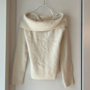 Offshoulder stickad tröja Gina Tricot  - Mysig offshoulder stickad tröja från Gina Tricot i en creme vit  färg. Tröjan har bred ribbad krage som går ner över axlarna och ribbade muddar vid ärmslut och nederkant. Perfekt för dig som gillar en chill och trendig look. Ny utan lapp 
