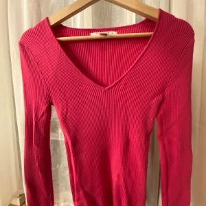 Ribbad rosa tröja från Amisu - Säljer en ribbad rosa långärmad tröja från Amisu med snygg v-ringning. Tröjan är i stickad kvalitet och har en slim passform som sitter riktigt snyggt. 